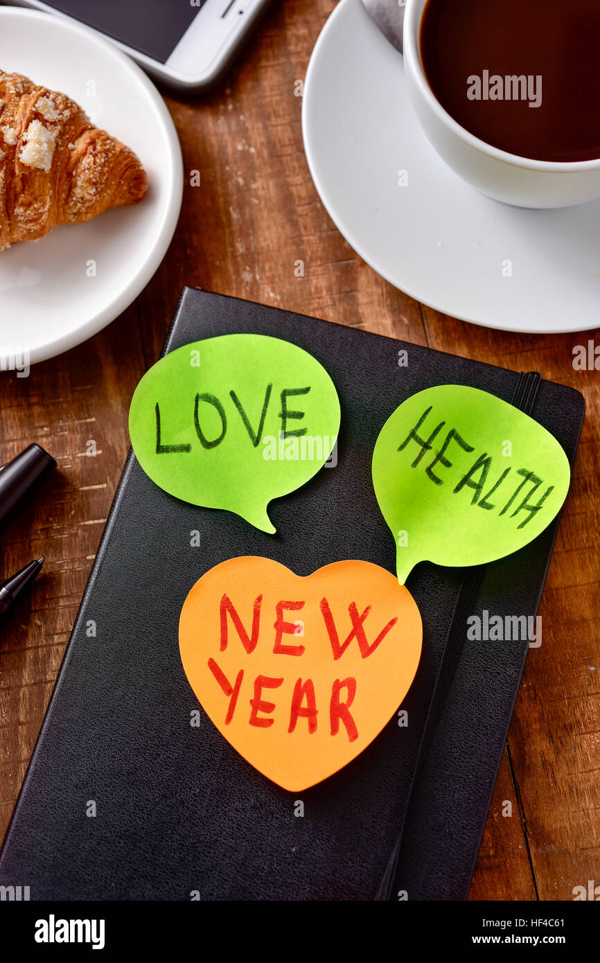 eine Notiz mit dem neuen Jahr Text und zwei weitere Haftnotizen mit dem Worte Liebe und Gesundheit als Wünsche für das neue Jahr angebracht, ein Notizblock, auf eine w Stockfoto