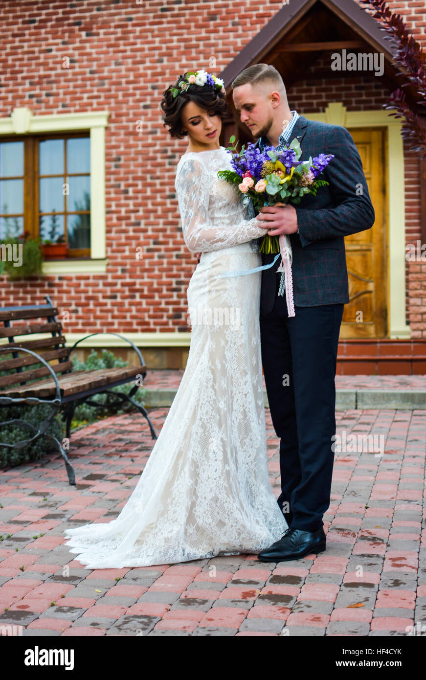 Porträt von emotionalen Brautpaar Bräutigam und die Braut umarmen einander Händchen. Im Hof gegen Haus in Herbstsaison. Stockfoto