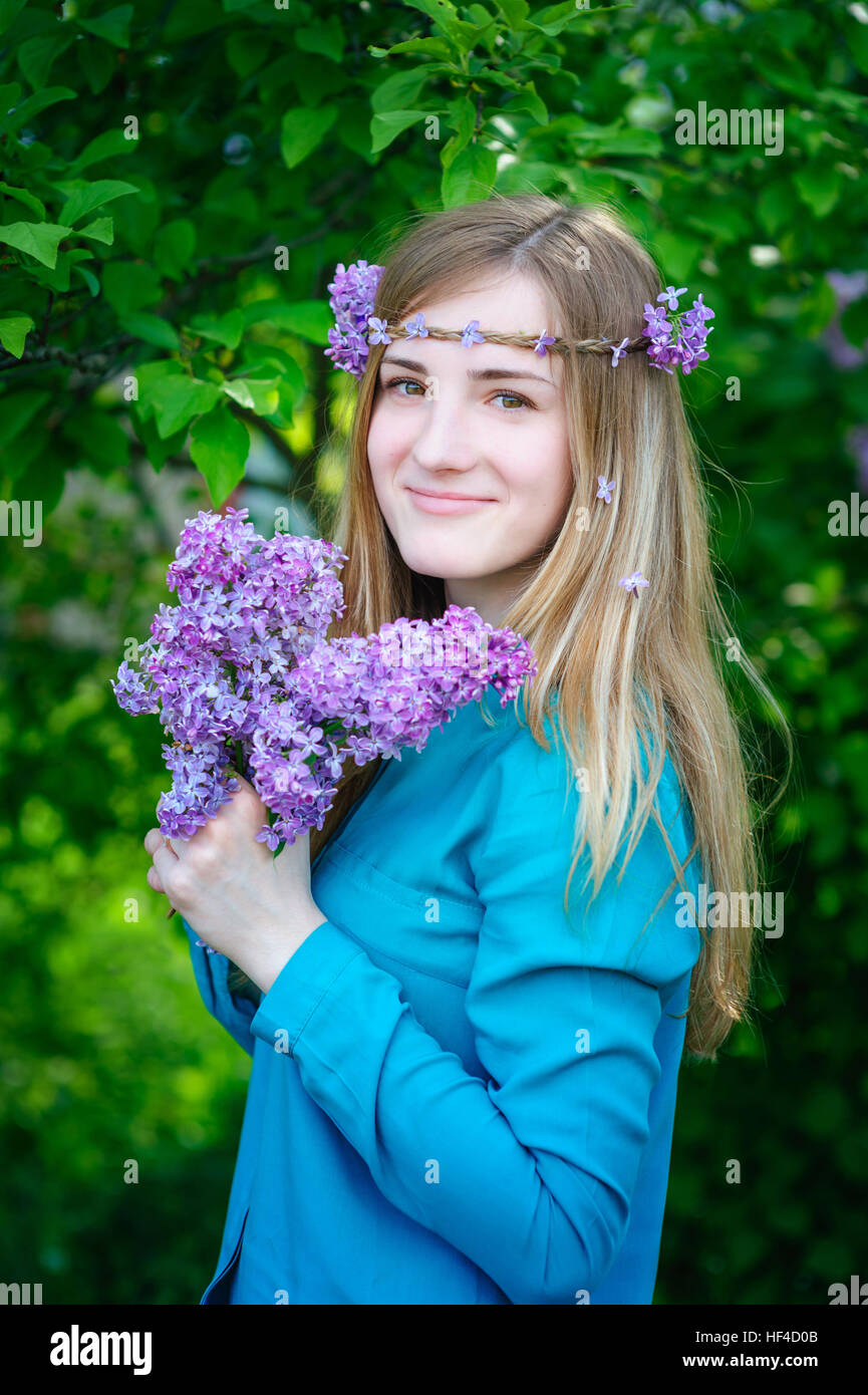 schöne junge Frau mit einem Bouquet von Flieder in Händen Frühlingsgarten Stockfoto