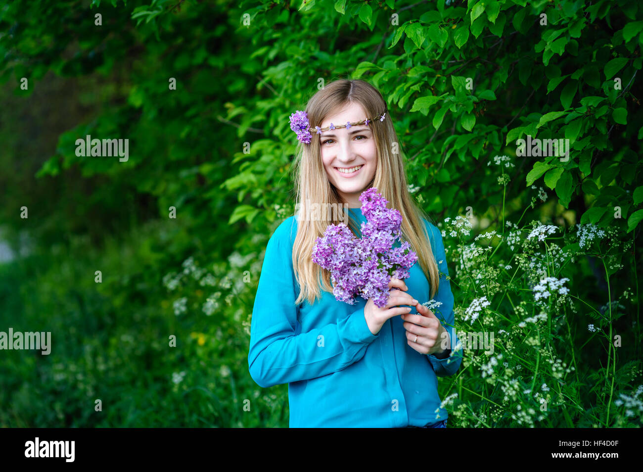 schöne junge Frau mit einem Bouquet von Flieder in Händen Frühlingsgarten Stockfoto