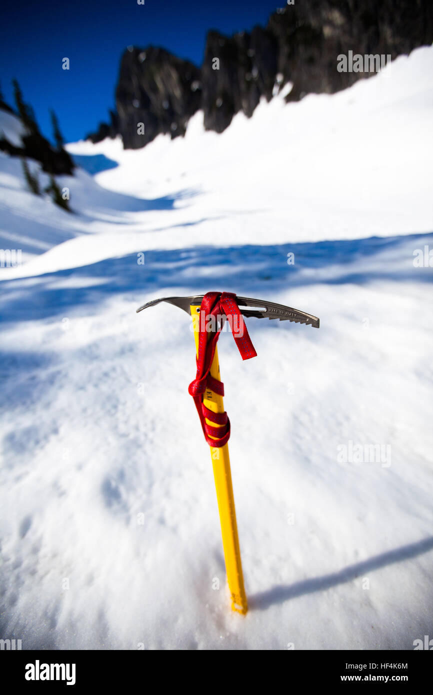 Ein Pickel ruht, gepflanzt im Schnee in einer Pause, während das Gipfel Ziel, den Zahn im Hintergrund, Snoqualmie Pass, WA Webstühle Stockfoto