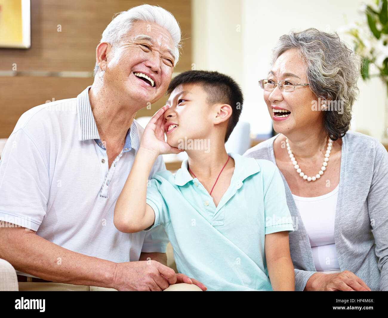 asiatische Enkel Flüstern, Großvater und Großmutter beobachten. Stockfoto