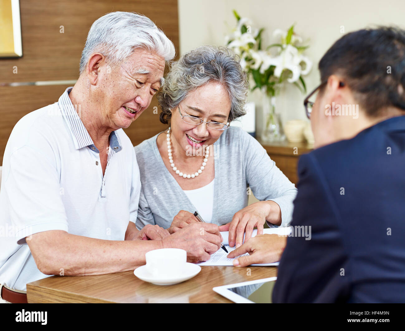 hochrangige asiatische Brautpaar unterzeichnen einen Vertrag vor einem Verkäufer. Stockfoto
