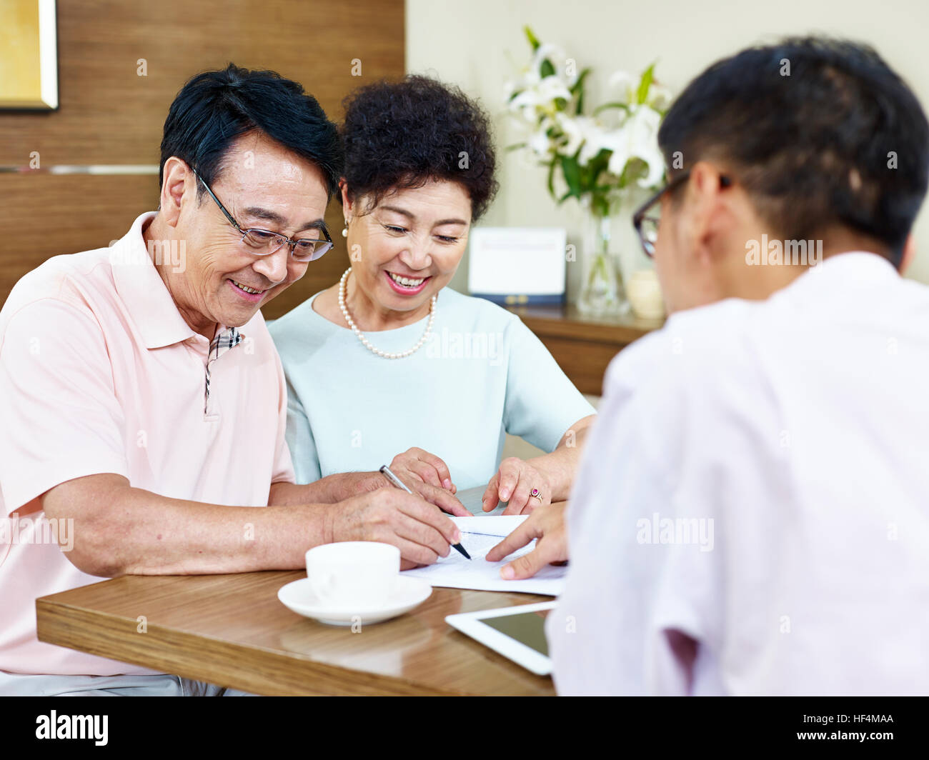 senior asiatischen Brautpaar einen Vertrag unterzeichnen in Front ein Vertriebsmitarbeiter. Stockfoto