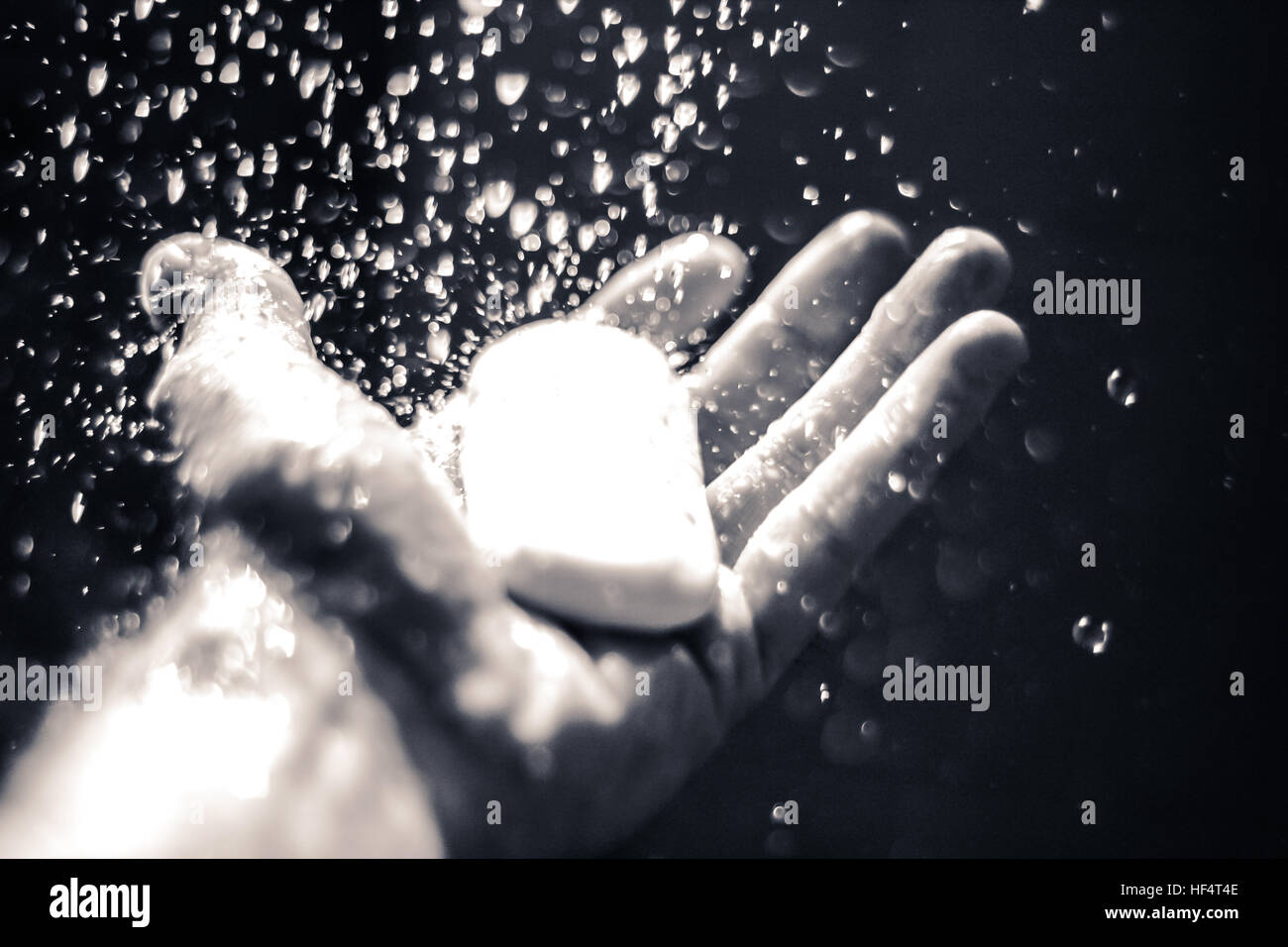 Foto von einer offenen menschlichen Hand mit Seife unter Wassertropfen Stockfoto