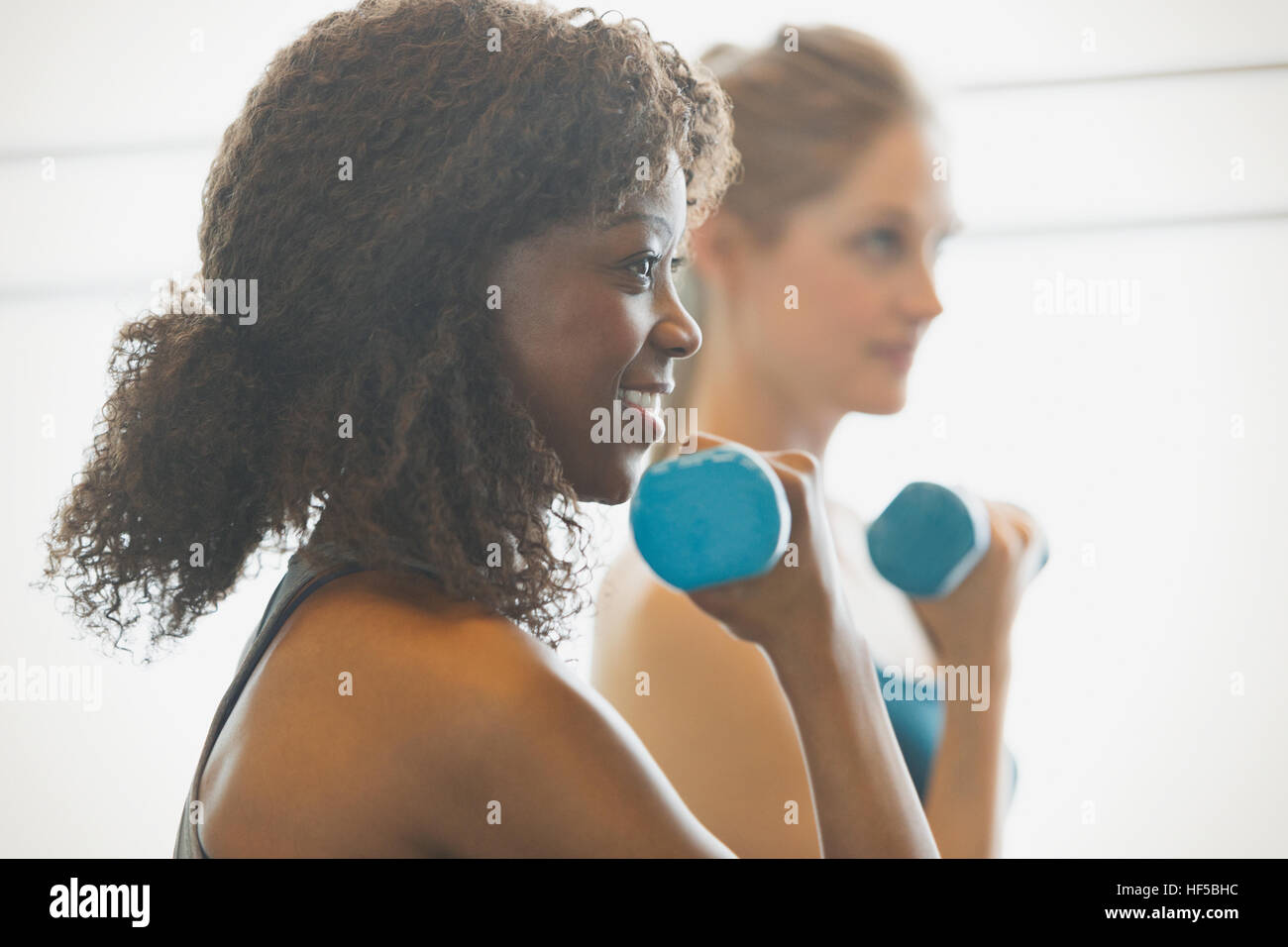 Lächelnde Frau tun Bizeps curls in Übung Klasse Gym studio Stockfoto