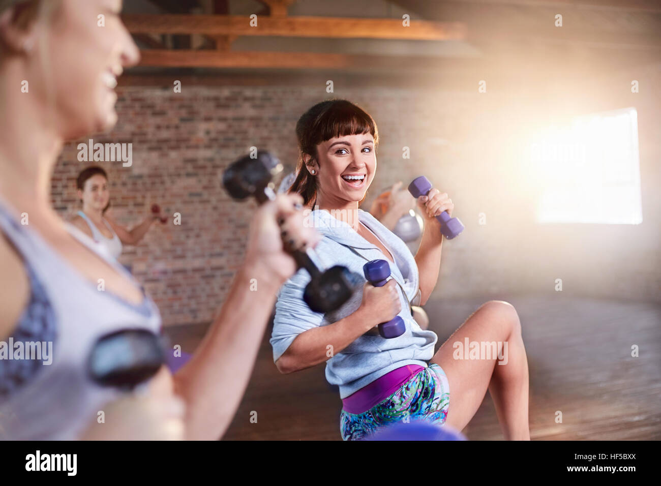 Lächelnde junge Frauen mit Hanteln in Übung Klasse Gym studio Stockfoto