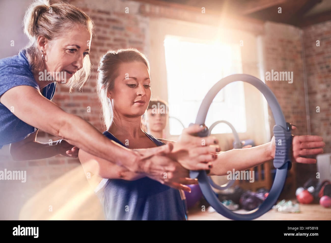 Fitness Instruktor helfende junge Frau mit Pilates Ring in Übung Klasse Gym studio Stockfoto