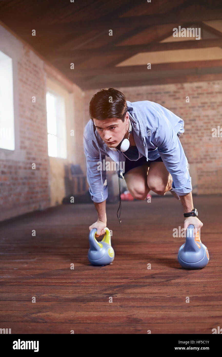 Junger Mann springt mit Wasserkocher Glocken im Fitness studio Stockfoto