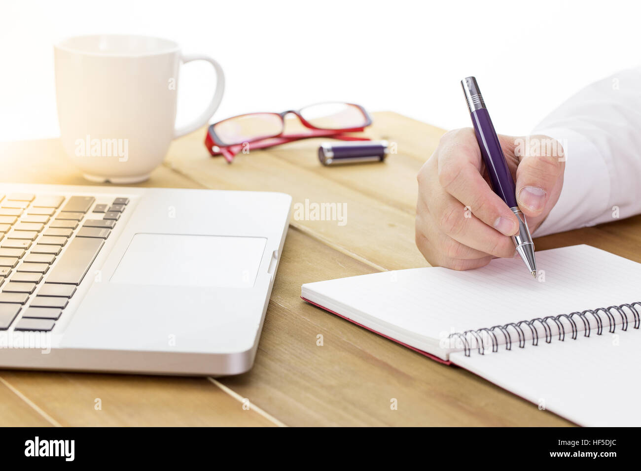 Geschäftsmann schreiben Sie eine kurze Notiz auf geöffneten Notizbuch mit Stift und Gläser. Warmton. Stockfoto