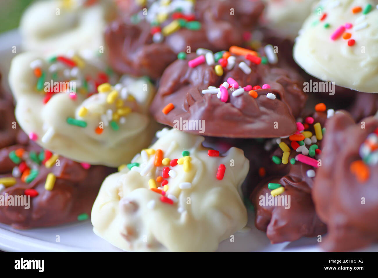 Nahaufnahme von weisser und Milchschokolade Bonbons mit Nüssen und Streuseln Stockfoto