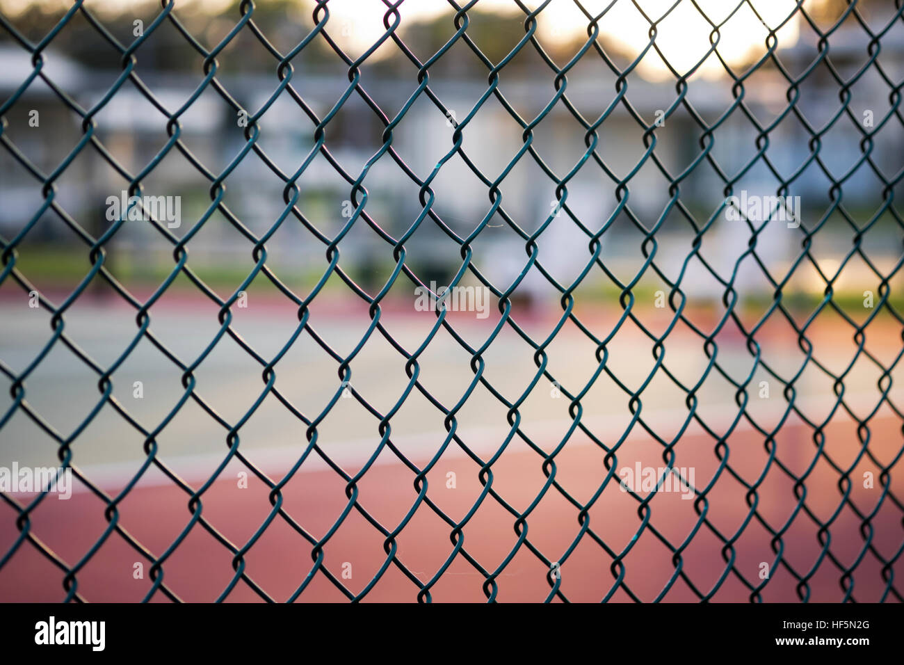 Maschendrahtzaun mit Tennisplatz im Hintergrund Stockfoto