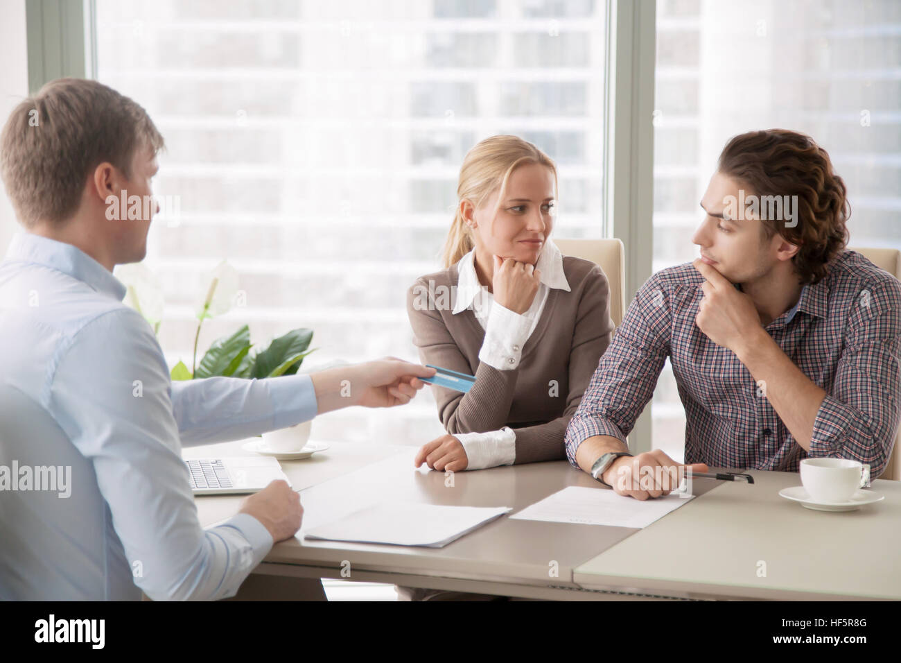 Junge Familie und Agent Übergabe einer Kreditkarte Stockfoto