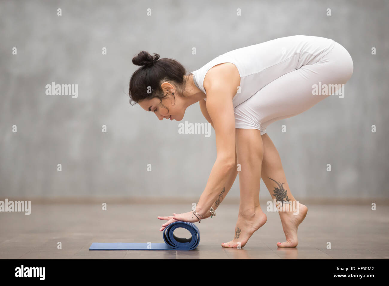 Schöne Yogi Frau Faltung ihrer Matte Stockfoto
