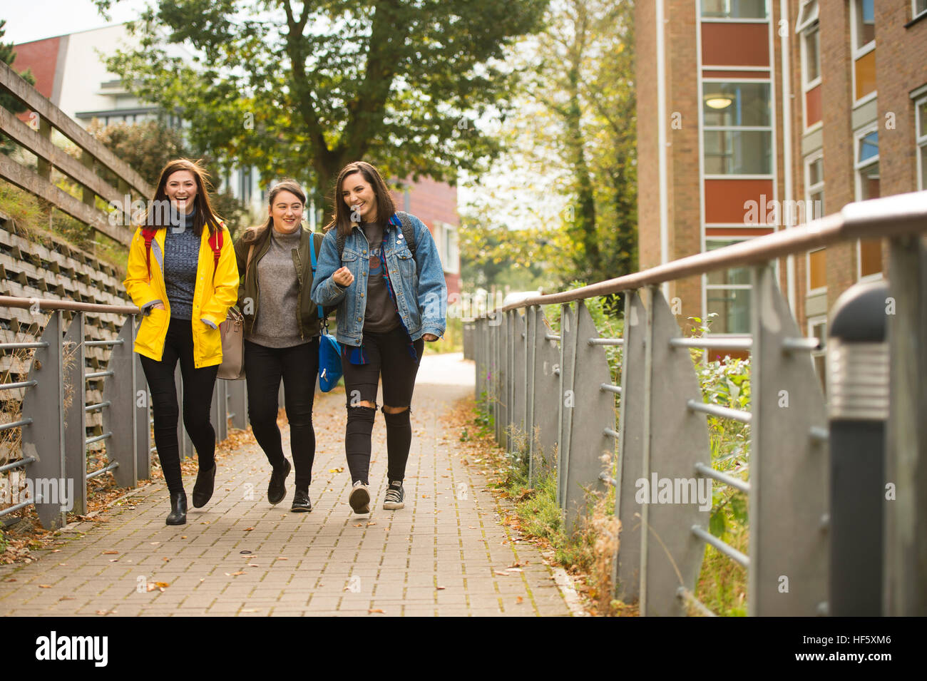 Hochschulbildung in Großbritannien: drei glücklich lächelnde lachende Aberystwyth University Frauen Studentinnen zu Fuß zu den Vorlesungen auf dem Campus Stockfoto