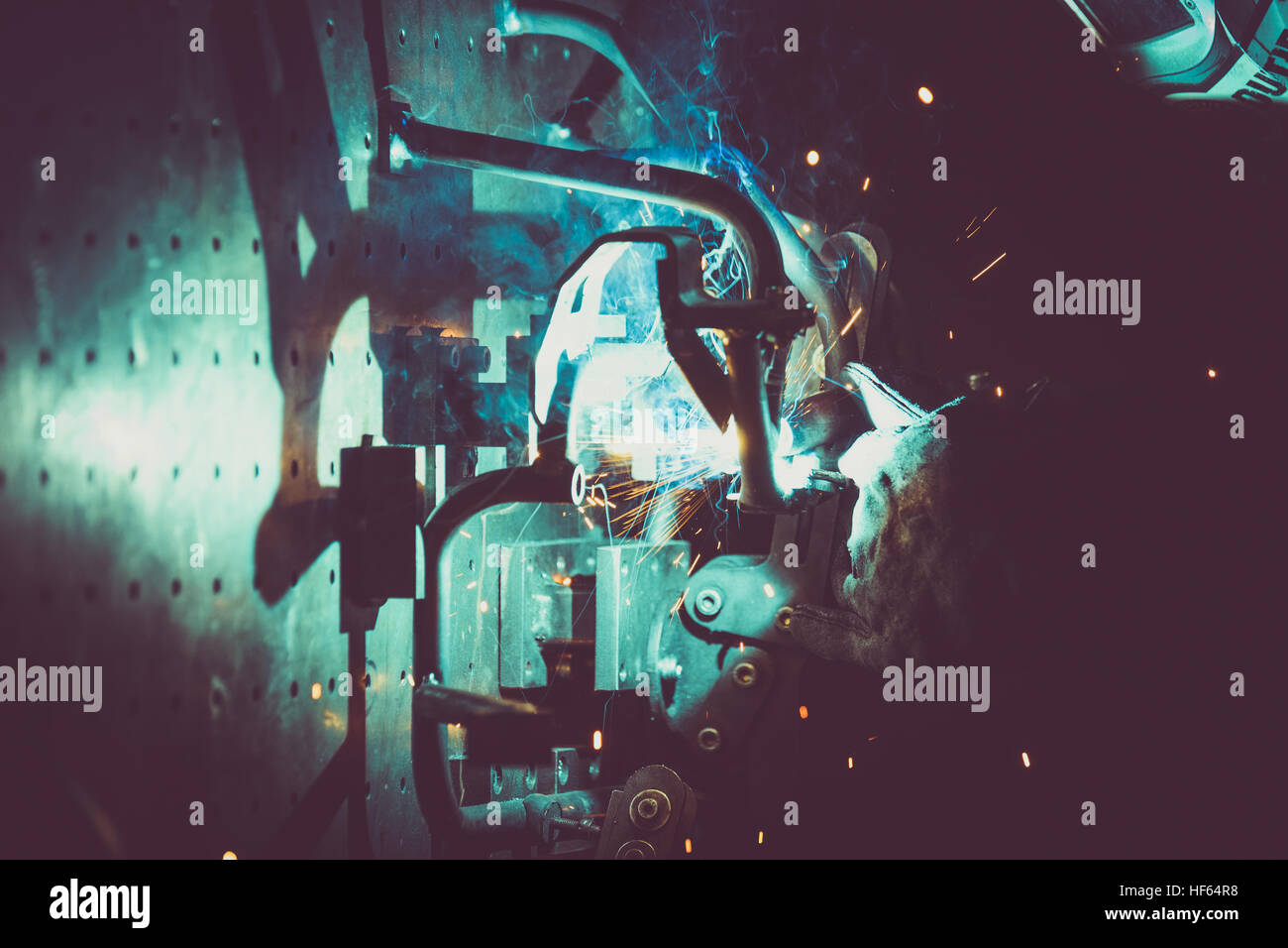Arbeiter mit Schutzmaske Schweißen Metall und Produktion von Rauch und Funken Stockfoto