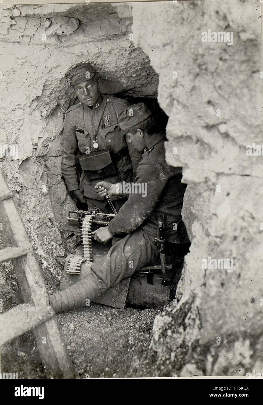 Ein Soldat, der während des Ersten Weltkriegs in einer Höhle einen Maschinengewehrgürtel nachlädt, unterstreicht die harten Bedingungen und die strategische Bedeutung unterirdischer Stellungen. Stockfoto