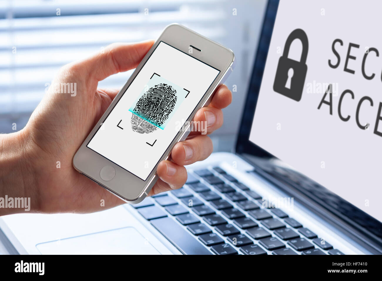 Person mit Fingerabdruck Scannen auf Handy für biometrische Sicherheit, Computer im Hintergrund Stockfoto