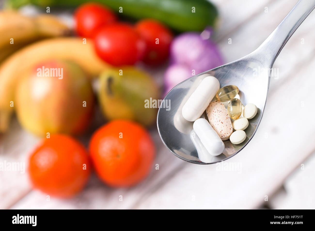 Silberlöffel mit Nahrungsergänzungsmitteln auf fruchtigen Hintergrund Stockfoto