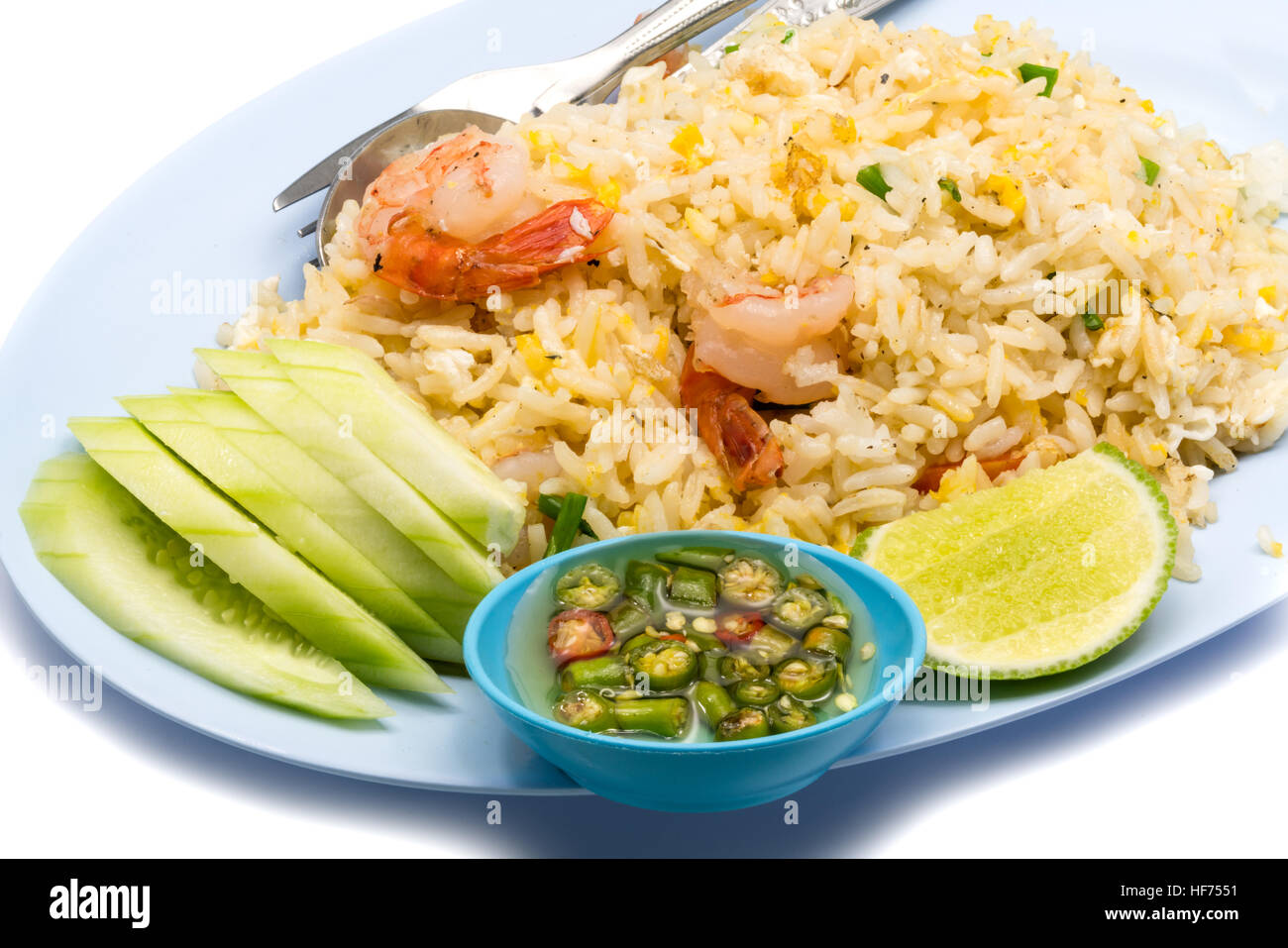 Gebratener Reis mit Garnelen, Ei, Gurke, Chili, Fischsauce und Zitrusfrüchte in einer blauen Platte auf weißem Hintergrund Stockfoto