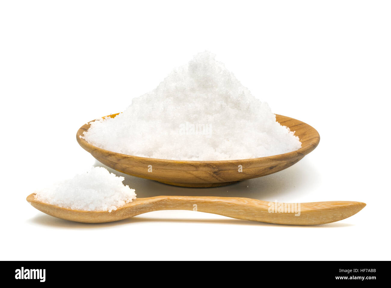 Weißes Salz in Holzplatte und Kochlöffel auf weißem Hintergrund Stockfoto