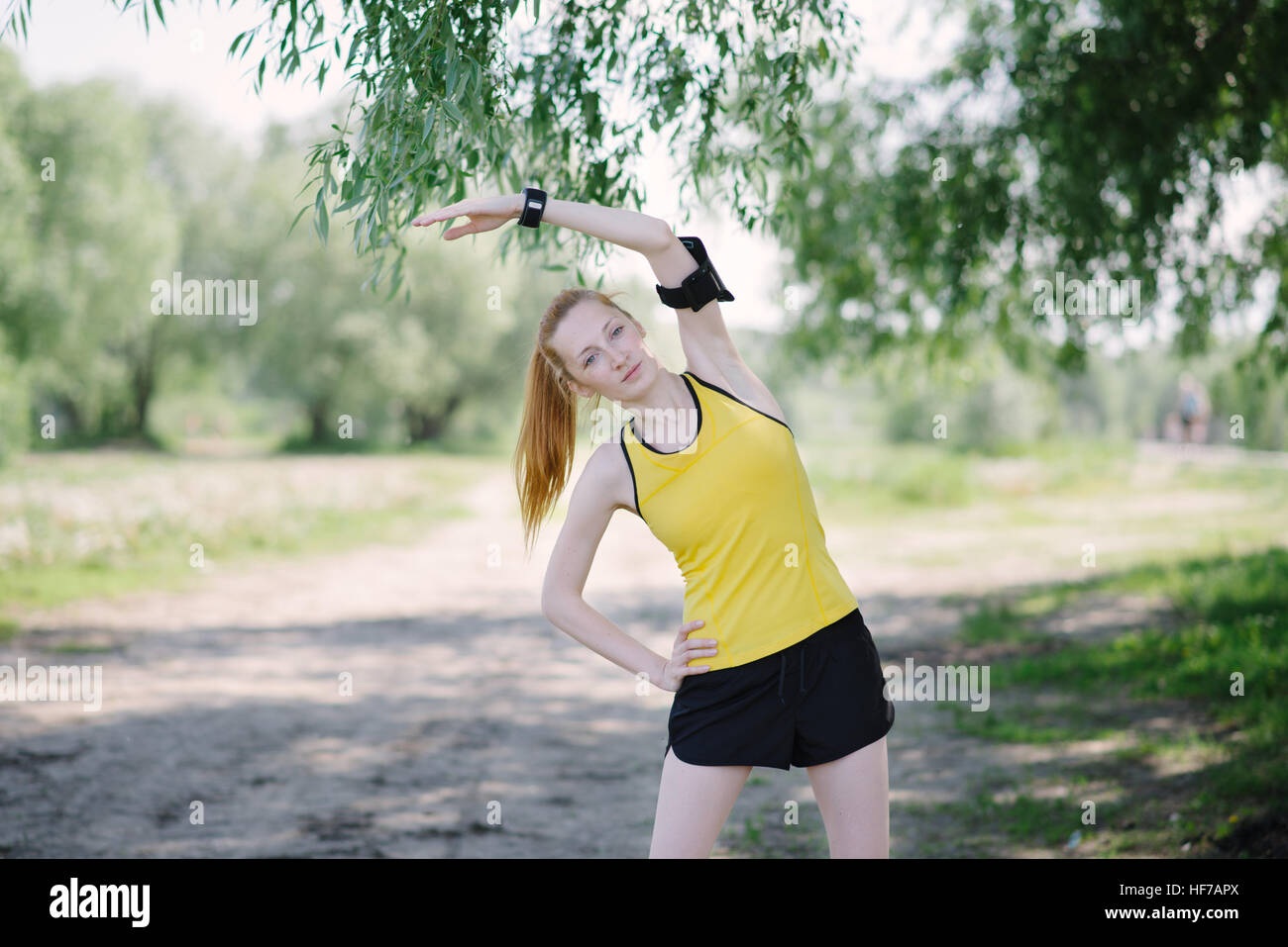Junge Fitness stretching Körper der Frau vor dem laufen. Sportler stehen unter Baum. Stockfoto