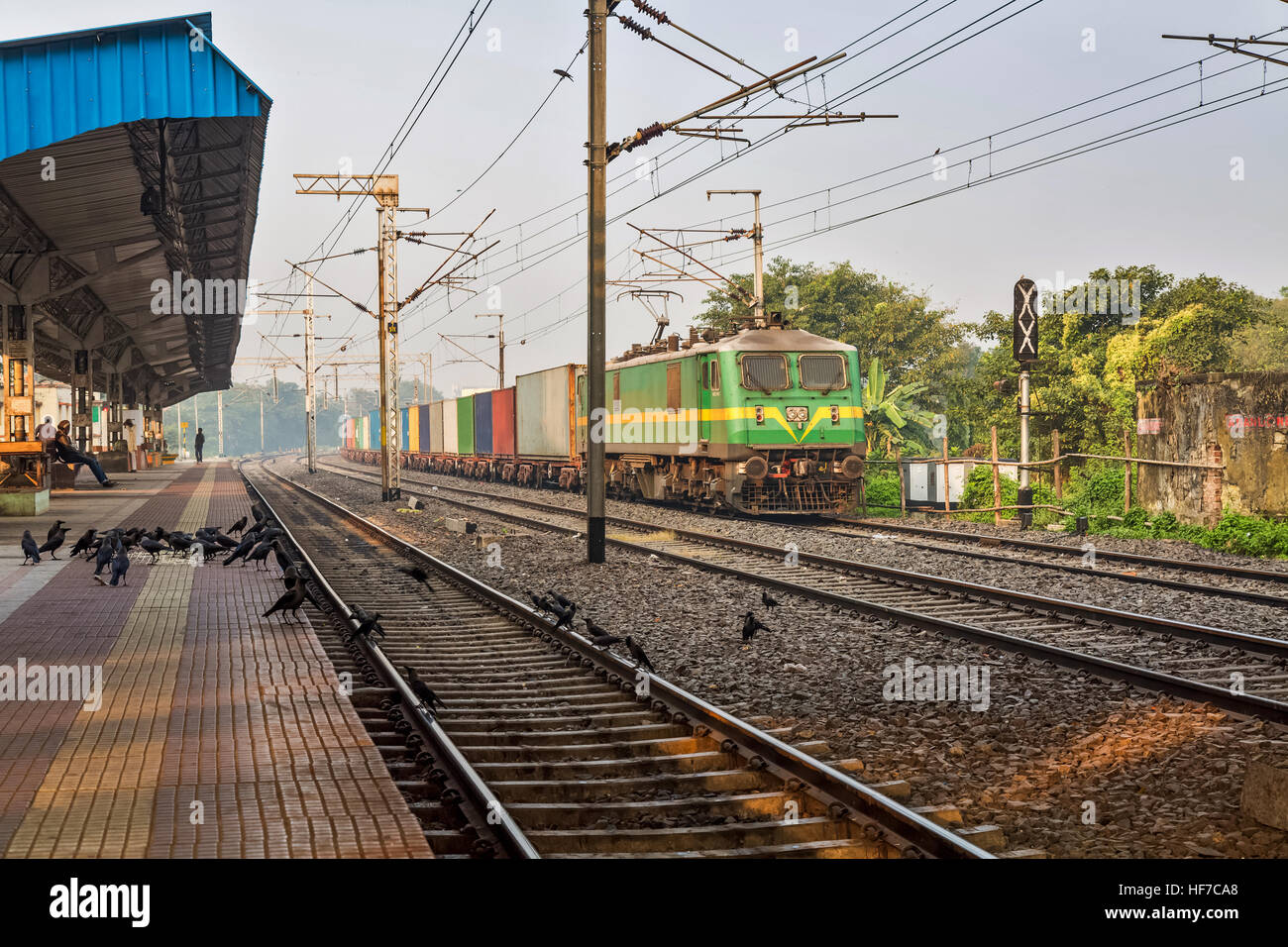 Güterzug der indischen Eisenbahn überqueren einen verlassenen Bahnhof an einem nebligen Wintermorgen. Stockfoto