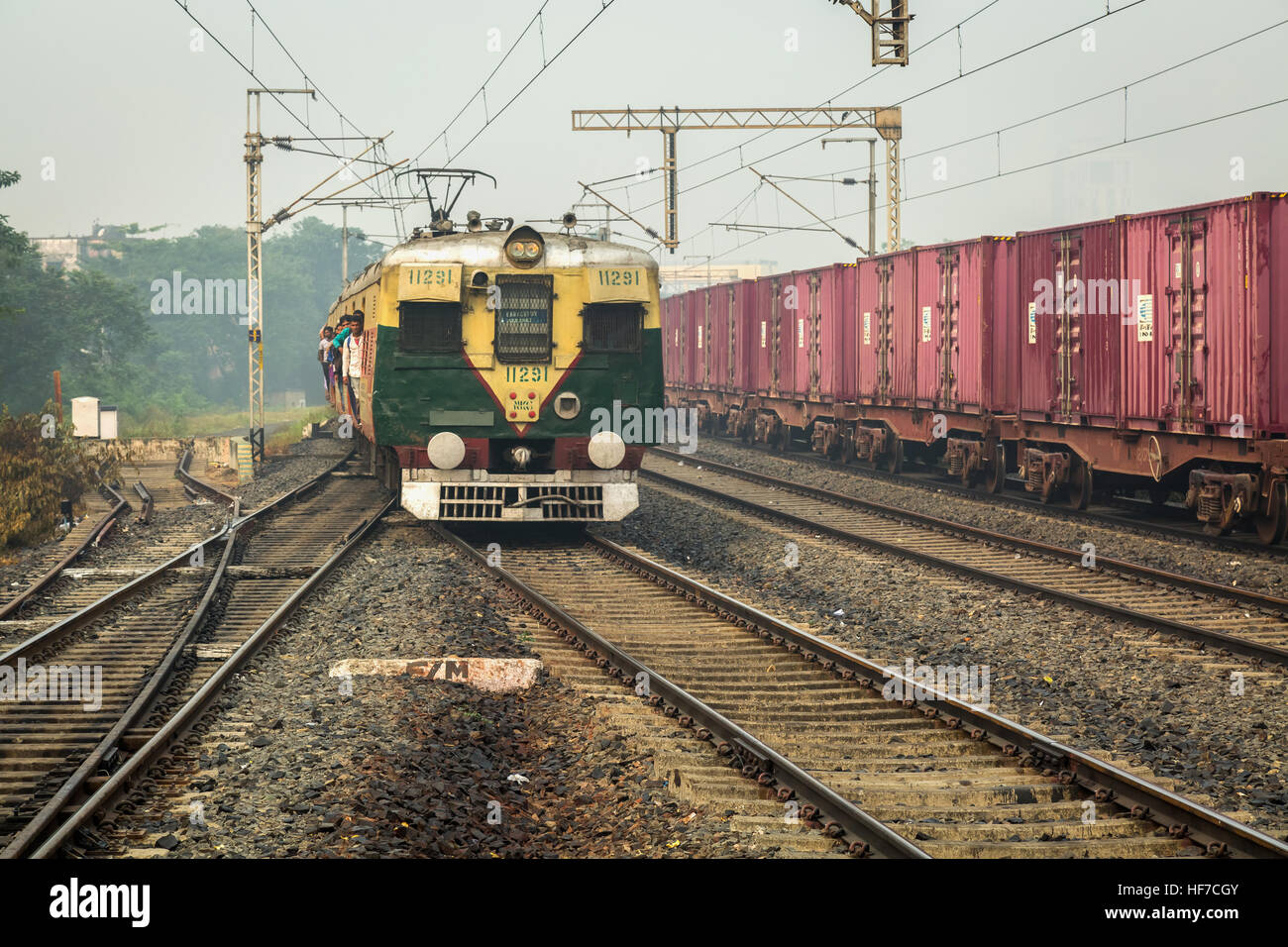 Überfüllten lokaler Personenzug der indischen Eisenbahnen eine Bahn-Bahnsteig an einem nebligen Wintermorgen zu betreten. Stockfoto