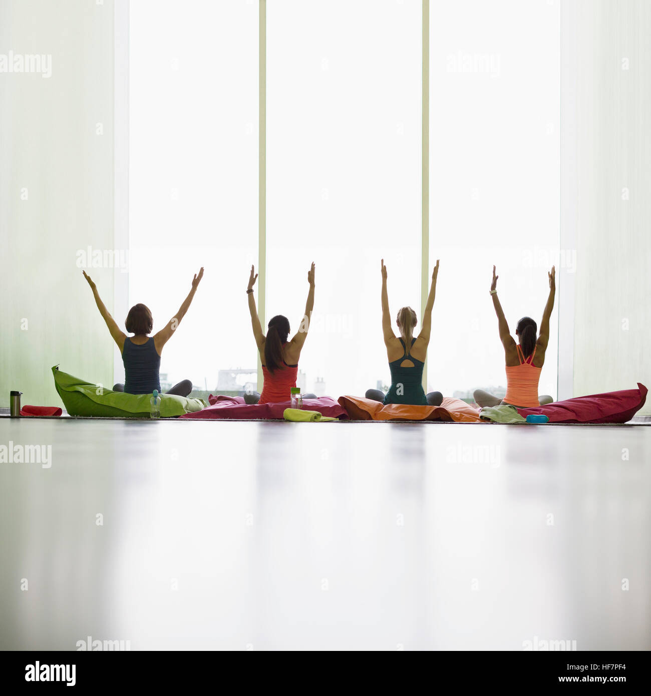 Frauen auf Kissen mit Restoratives Yoga Fitness Studio erhobenen Armen Stockfoto