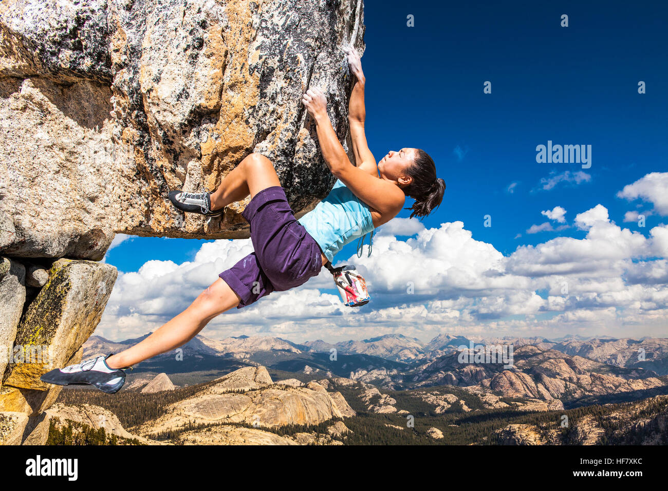 Weibliche Kletterer baumelt von der Kante einer anspruchsvollen Klippe. Stockfoto