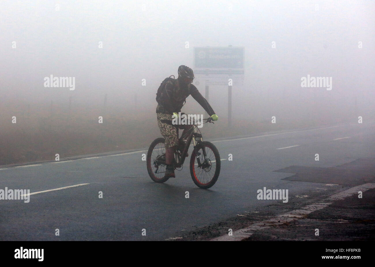 Calderdale, UK. 30. Dezember 2016. Ein Radsportler, die über eine stark befahrene Straße in Nebel, Saddleworth, 30. Dezember 2016 (C) Barbara Koch/Alamy Live News Stockfoto