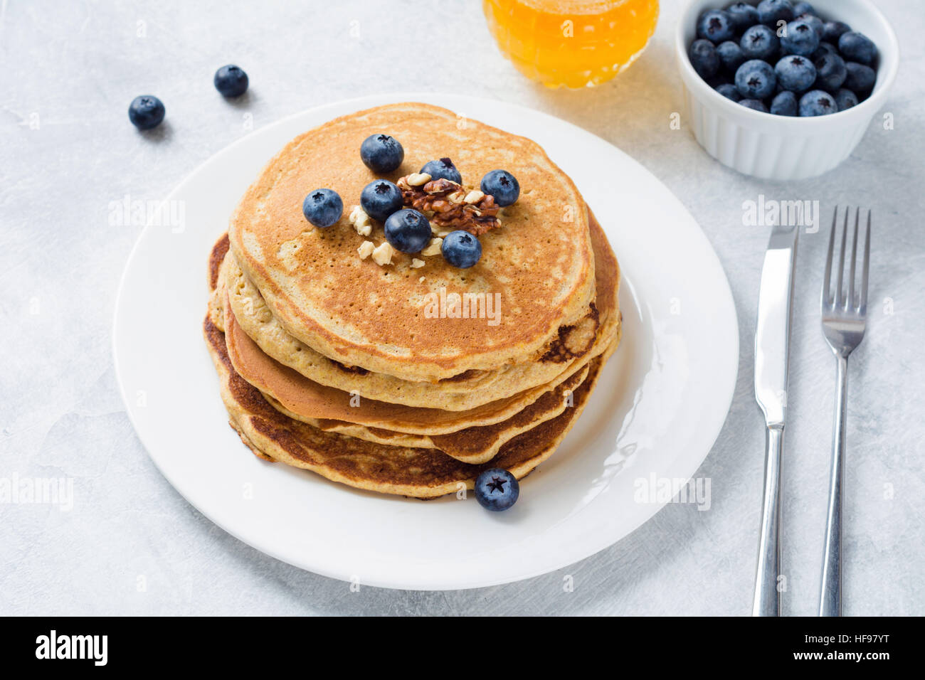 Stapel von Pfannkuchen mit frischen Heidelbeeren, Nüssen und Honig auf weißen Teller. Gesundes Frühstück Essen. Stockfoto