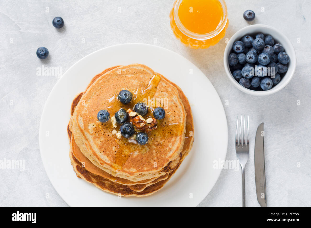 Stapel von Pfannkuchen mit frischen Heidelbeeren, Nüssen und Honig auf weißen Teller. Gesundes Frühstück Essen. Stockfoto