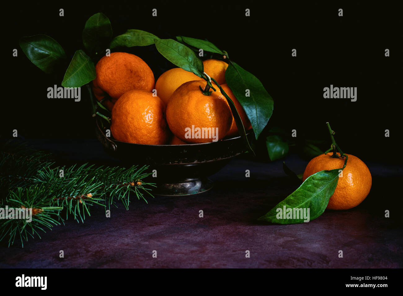 Stillleben mit frischen Mandarinen mit grünen Blättern in Vintage Metallschale. Getönten Bild, low-Key-Technik (Chiaroscuro) Stockfoto