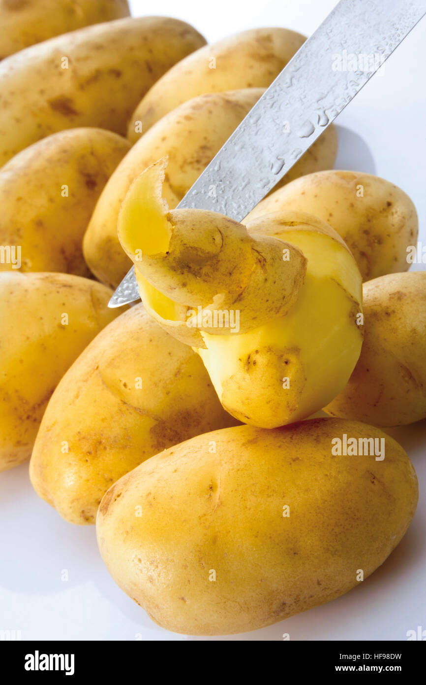 Kartoffeln (Solanum Tuberosum), eine Hälfte geschält und ein Messer Stockfoto
