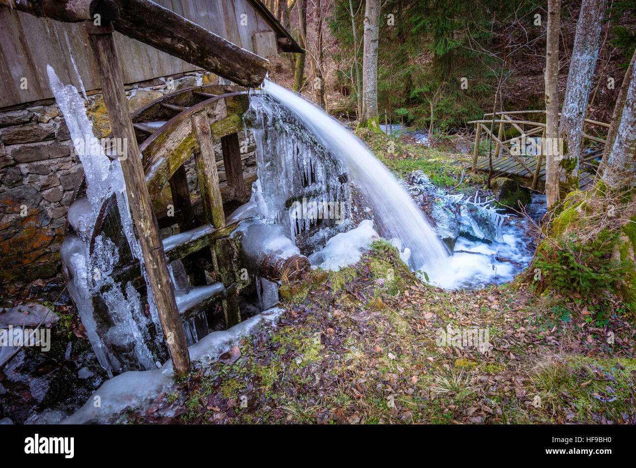 Alten Wasserrad antreiben einer Mühle, mit Wasser, das durch einen hölzernen Trog. Im Winter vereist. Stockfoto