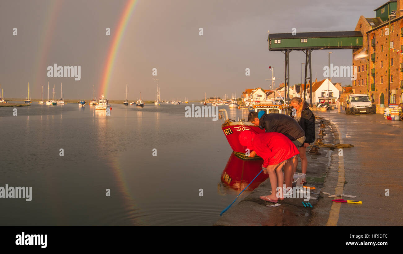 Krabben aus der Hafenmauer als bildet sich ein Regenbogen über Wells-Next-the-Sea bei einem Sommer-Abend-Sturm. Stockfoto
