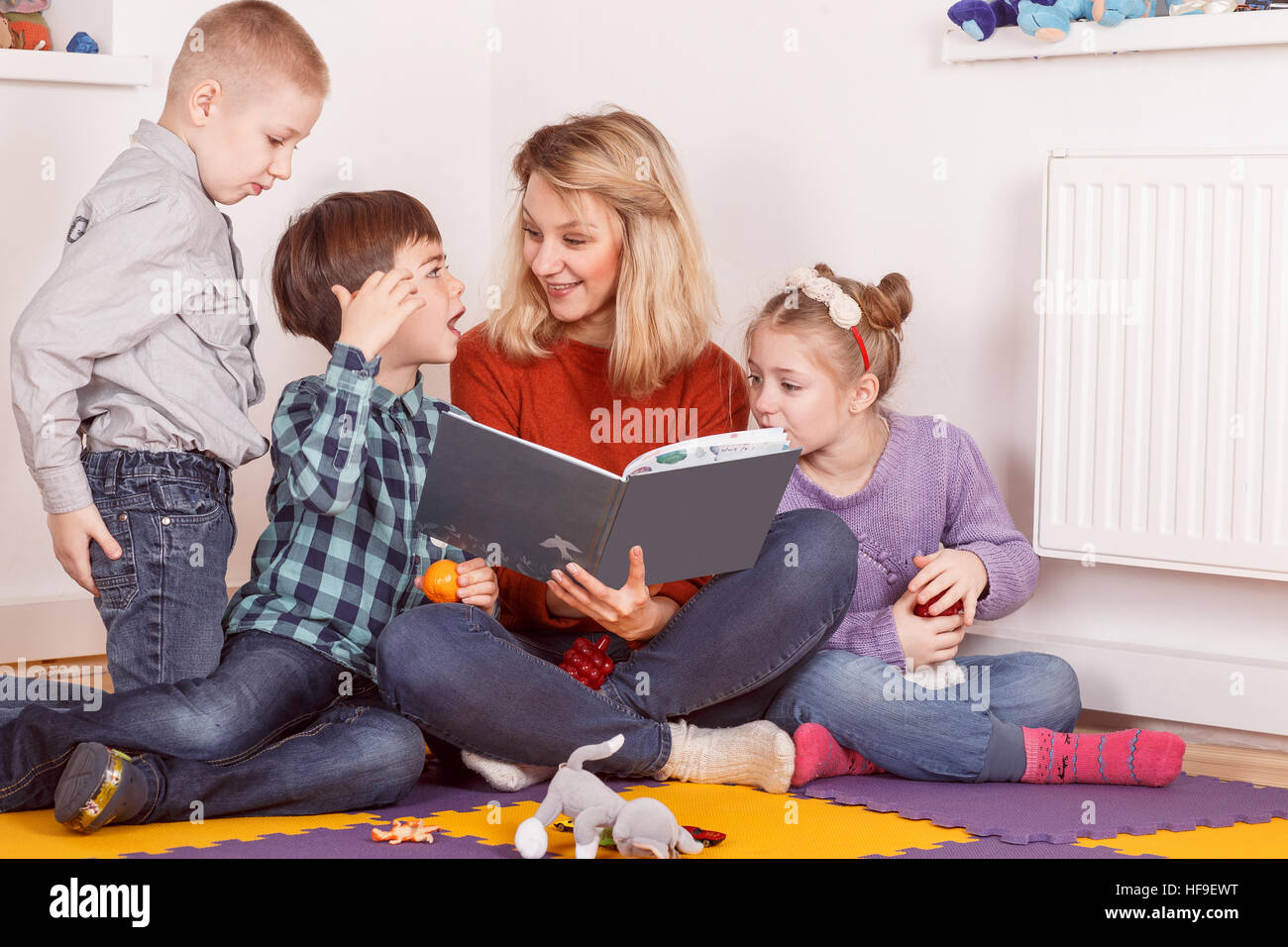 Junge Frau mit drei Kindern ein Buch zu lesen Stockfoto