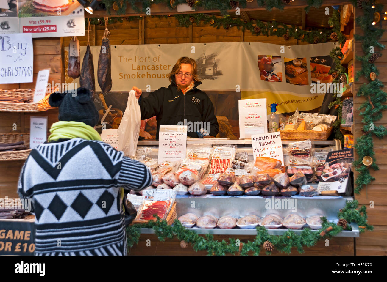 Shopper kaufen Fleisch am Weihnachtsmarkt Händler Stand in St. Nicholas Fayre im Winter York North Yorkshire England Vereinigtes Königreich Großbritannien GB Großbritannien Stockfoto