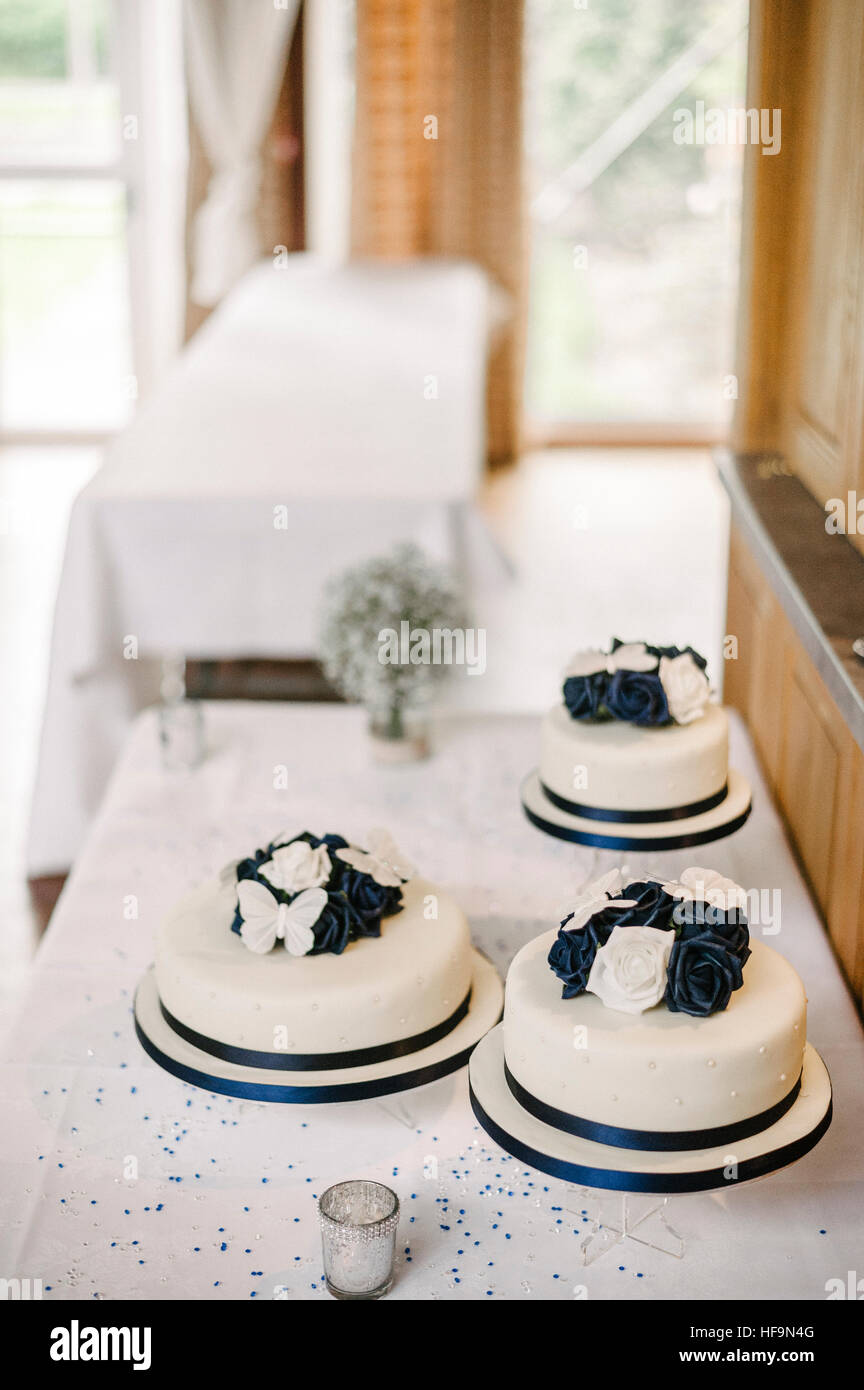 Drei weiße Hochzeitstorten mit weißen und blauen Tortenaufsätze. Stockfoto