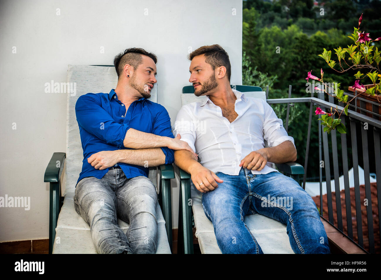 Homosexuelle Paare auf Stühlen auf Balkon Stockfoto