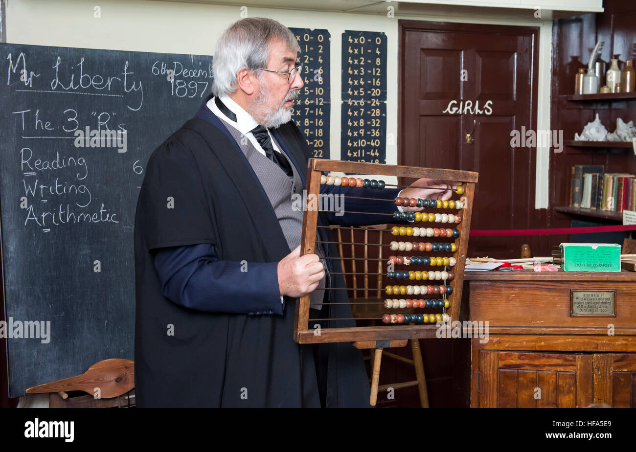 Eine Nachbildung einer viktorianischen Klassenzimmer. Ein Lehrer unterrichtet Mathematik mit einem Abakus. Stockfoto