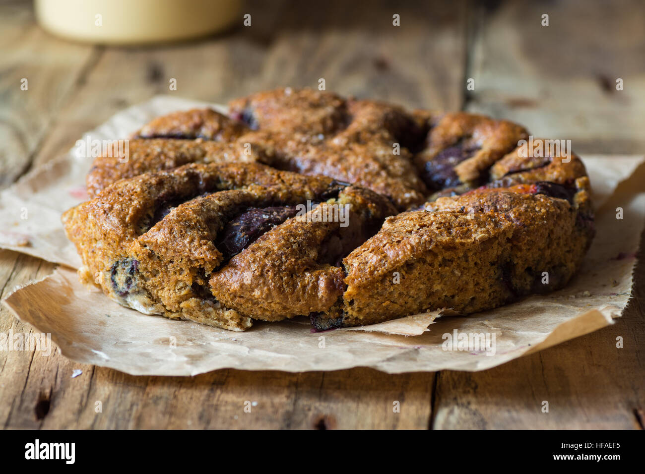 Hausgemachte eifreie Pflaumenkuchen aus Vollkorn auf gewachsten Pergamentpapier auf Holztisch im Alter von Plank, rustikale Vintage-Stil, Verwandten Stockfoto