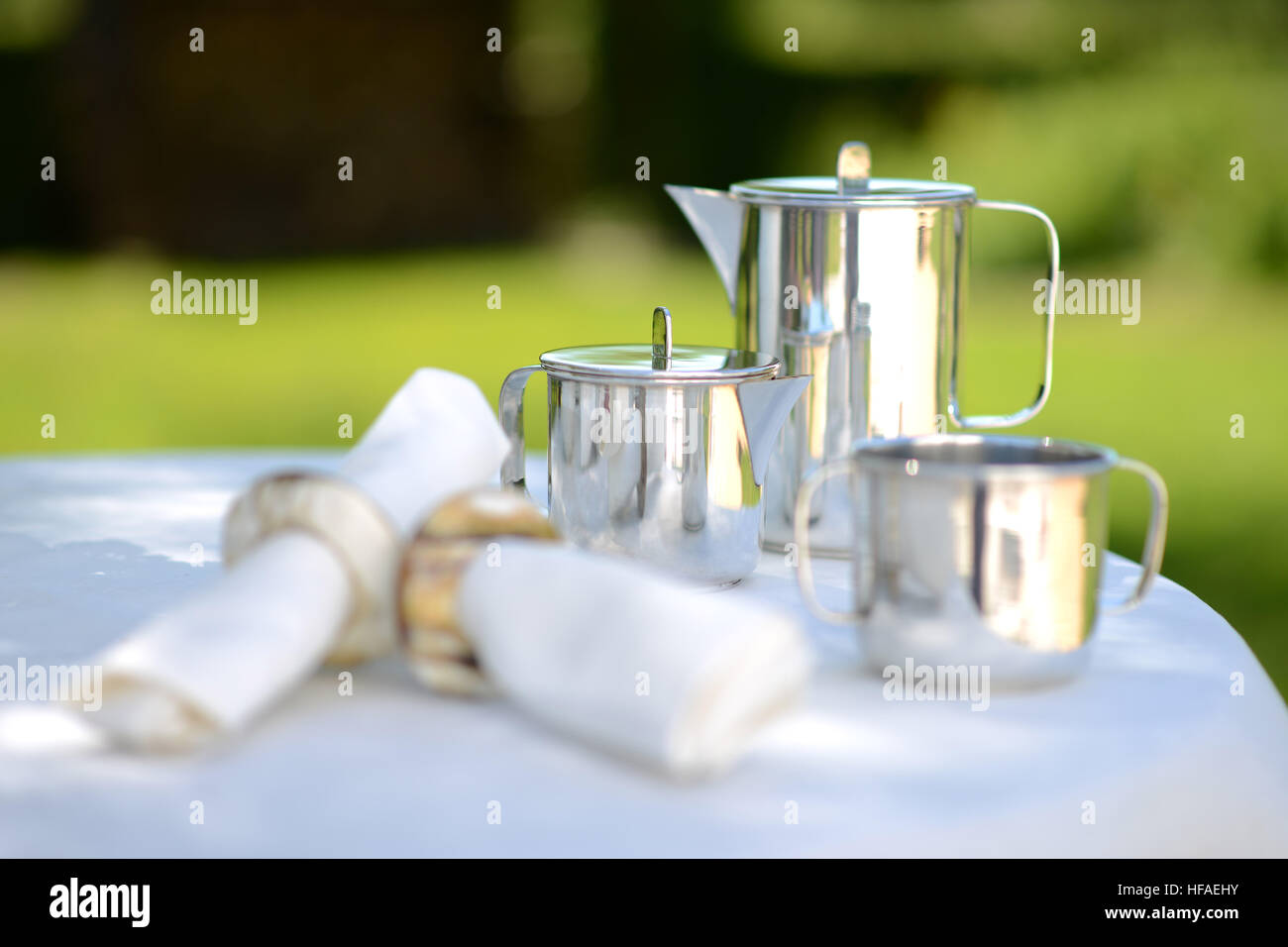 Luxus Silberne Kaffeekanne auf einen Leinen gedeckten Tisch draußen im Sommer. Stockfoto