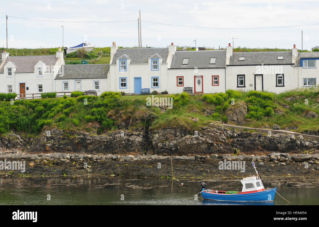 Eine Reihe von bemalten Häuschen am Rande der geschützten Hafen bei portnahaven. Portnahaven, Islay, Innere Hebriden, Argyll, Schottland, Großbritannien. Stockfoto