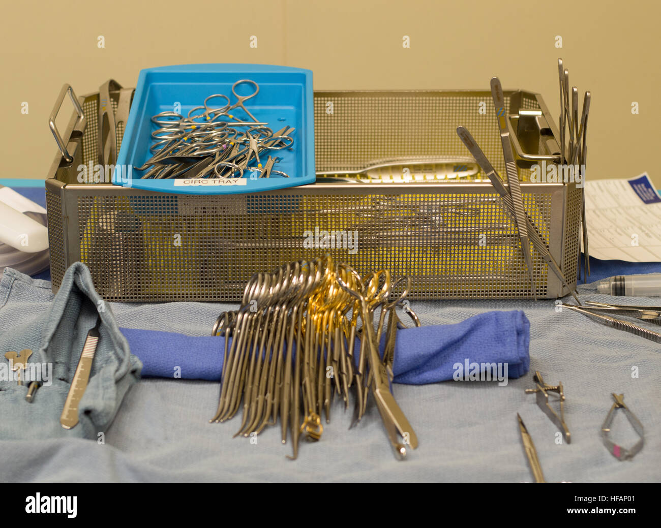 Sterile chirurgische Instrumente mit einer Metall-Pfanne im Hintergrund und steril drapiert auf OP-Tisch im Vordergrund. Stockfoto