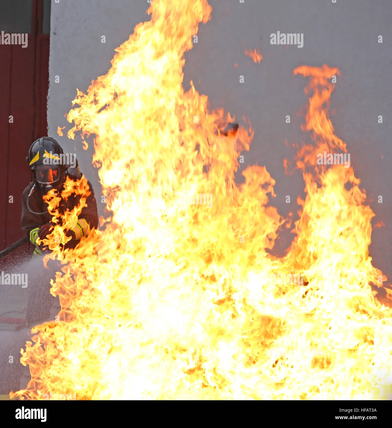 Feuerwehrmann hinter einem riesigen Feuer mit hohen Flammen sehr heiß Stockfoto