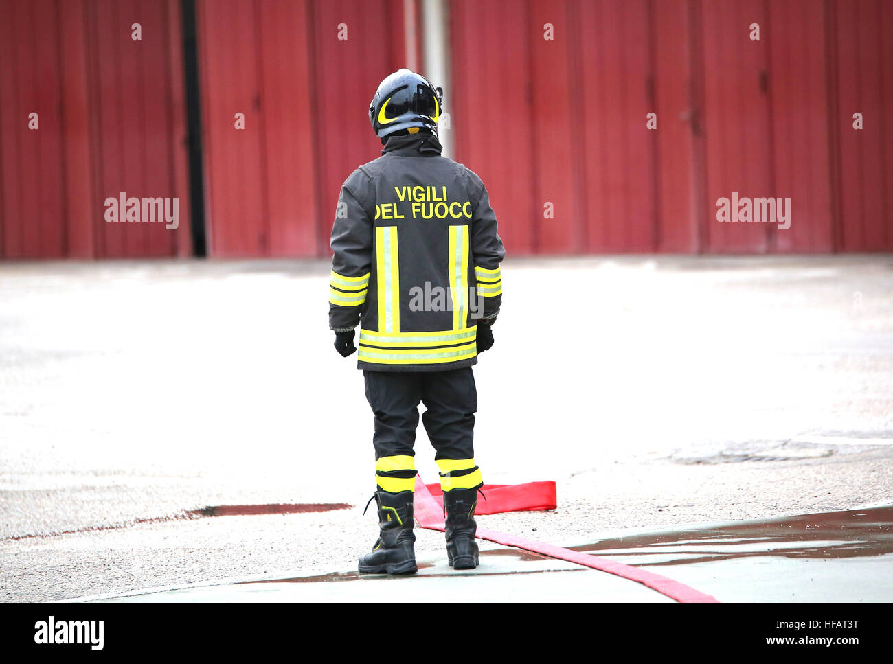 einsame italienische Feuerwehrleute mit den roten Feuerwehrschlauch mit den Worten in die schützende Kleidung, die Feuerwehrleute in italienischer Sprache bedeutet Stockfoto