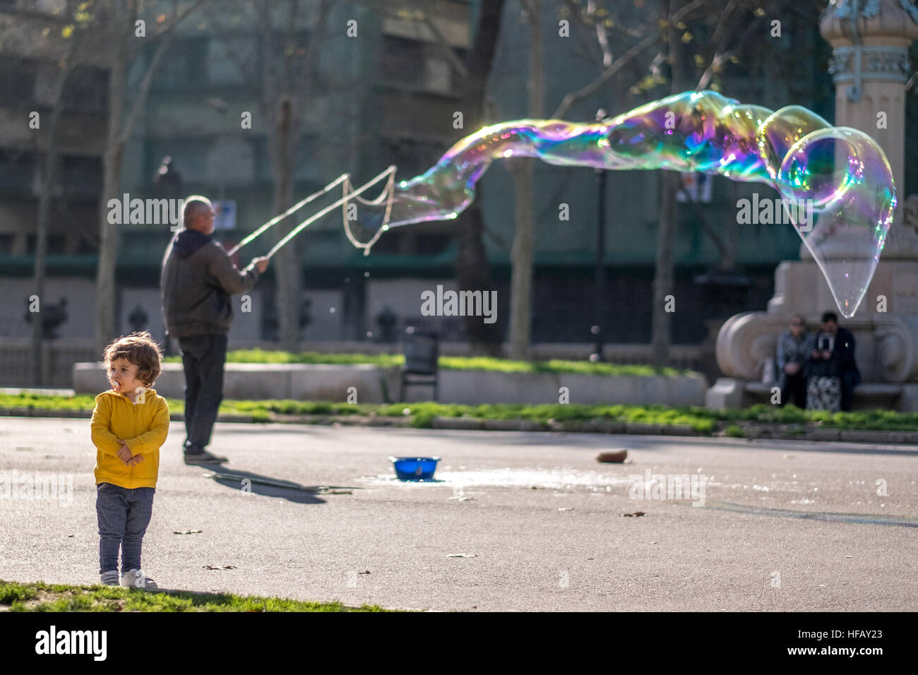 Ein Mann macht eine riesige Seifenblase in einem sonnigen Park. Stockfoto