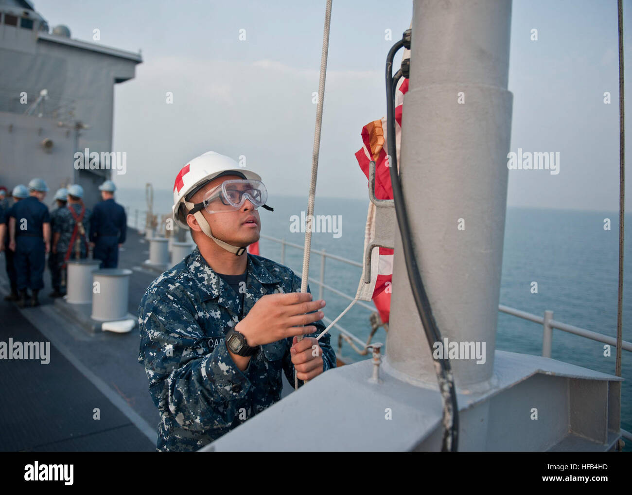 Hospitalman Andrew E. Carpio, zugeordnet der medizinischen Abteilung an Bord der amphibischen Dock Landungsschiff USS Germantown (LSD-42), wirft der Union Jack Flagge während der Morgen-Farben. Germantown ist vor Anker vor der Küste Pulau Pangkor, Malaysia in Vorbereitung für die Zusammenarbeit über Wasser Bereitschaft und Training Malaysia 2012. Karat 2012 ist eine neun-Land, bilaterale Übung zwischen den Vereinigten Staaten und Bangladesch, Brunei, Kambodscha, Indonesien, Malaysia, Singapur, den Philippinen, Thailand und Timor-Leste und dient zur Verbesserung der Sicherheit im Seeverkehr Fähigkeiten und operativen Geschlossenheit unter Informationsabend Stockfoto